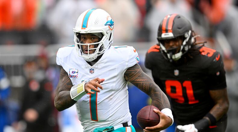 Miami Dolphins quarterback Tua Tagovailoa (1) scrambles from Cleveland Browns defensive end Alex Wright (91) in the first half of an NFL football game in Cleveland, Sunday, Oct. 19, 2025. (AP Photo/David Richard)