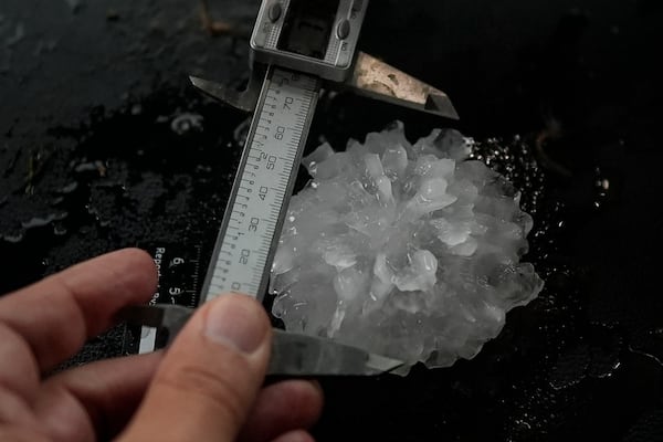 Forensic engineer Tim Marshall measure a large hail shaped like a rose between the front seats of Northern Illinois University's Husky Hail Hunter during a Project ICECHIP operation Friday, June 6, 2025, in Morton, Texas. (AP Photo/Carolyn Kaster)