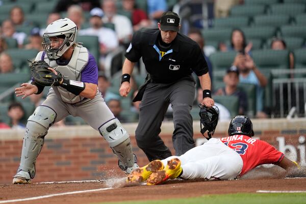 Atlanta Braves Ronald Acuña Jr. (13) slides to home plate against Colorado Rockies catcher Hunter Goodman (15) in the first inning of a baseball game, Friday, June 13, 2025, in Atlanta. (AP Photo/Mike Stewart)