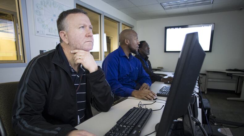 Systems engineers (from left) Andy Clement, 47, Corey English, 42, and Jerry Thomas, 63, monitor screens at the DeKalb County school district’s William Bradley Bryant Center for Technology in Decatur on Wednesday, Dec. 6, 2017. (CASEY SYKES, CASEY.SYKES@AJC.COM)