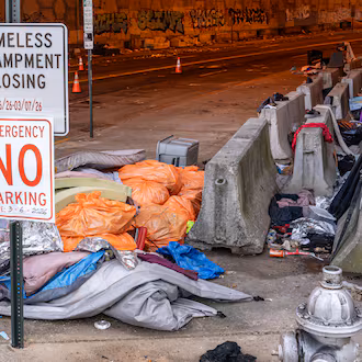 Trash is seen littered around a homeless encampment that runs along Leonard Tate Street under I-85 in downtown Atlanta. In recent years, homelessness policy in some of Georgia’s largest cities has drifted toward selective enforcement, guest columnist Victor Riches writes. (Ben Hendren for the AJC)