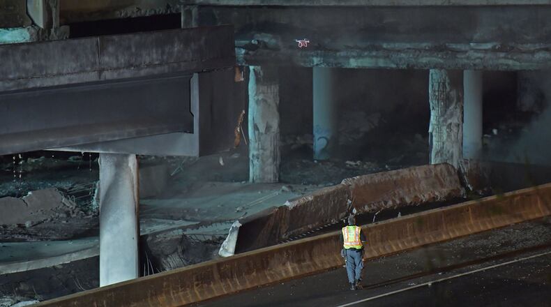 March 30, 2017 Atlanta - Crew surveys the section of an overpass that collapsed from a fire on I-85 on Thursday, March 30, 2017. Fire officials extinguished a massive fire on I-85 on Thursday night after it burned for more than an hour and led to the collapse of a bridge on the interstate, fire officials said. HYOSUB SHIN / HSHIN@AJC.COM