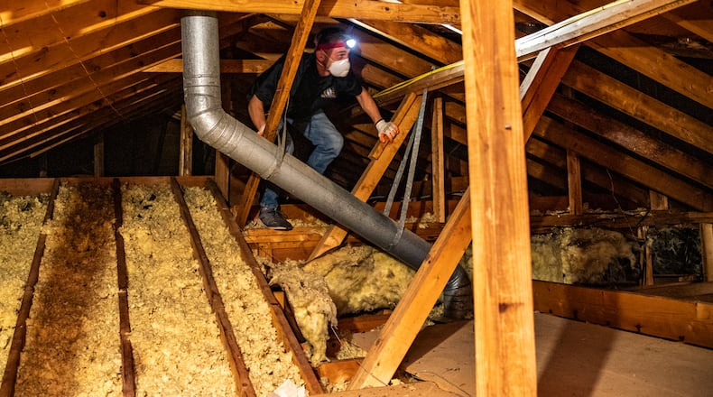 Ben Reeves looks for ventilation fans to seal and route outside before adding insulation to the attic of this Roswell home on Wednesday, April 19, 2023. New federal tax credits for home energy improvements incentivize homeowners to invest in an energy audit and update air leaks, add insulation and improve home efficiency to get federal tax credits, rebates and other financial benefits. (Jenni Girtman for the AJC 2023)