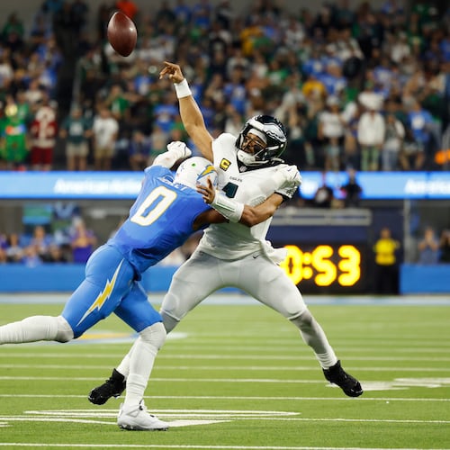 Philadelphia Eagles quarterback Jalen Hurts (1) throws as he is tackled by Los Angeles Chargers linebacker Daiyan Henley (0) during the first half of an NFL football game Monday, Dec. 8, 2025, in Inglewood, Calif. (AP Photo/Caroline Brehman)