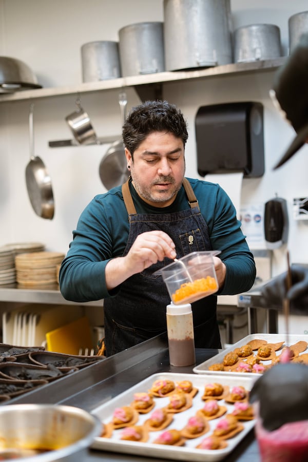 A chef wearing an apron looking down at the food he is preparing in a commercial restaurant kitchen.