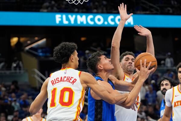 Orlando Magic forward Tristan da Silva, center, is fouled as he goes up for a shot against Atlanta Hawks forward Zaccharie Risacher (10) and forward Georges Niang, right, during the second half of an NBA play-in tournament basketball game, Tuesday, April 15, 2025, in Orlando, Fla. (AP Photo/John Raoux)