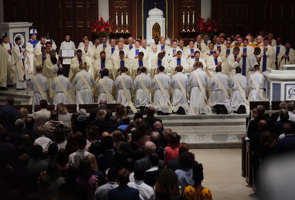 Priests and bishops bless the 12 newly ordained priests during Mass at the Cathedral of Saint Thomas More in Arlington, Va., on Saturday, June 7, 2025. (AP Photo/Jessie Wardarski)