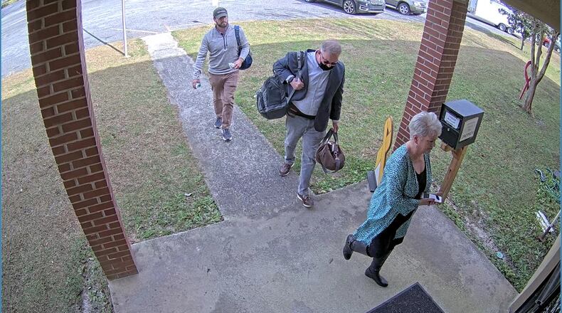 Scott Hall, a bail bondsman who flew from Atlanta to Coffee County and helped coordinate copying of election data, carries bags into the Coffee County elections office on Jan. 7, 2021. He's escorted by Cathy Latham, a fake elector for Donald Trump, and an unidentified man.