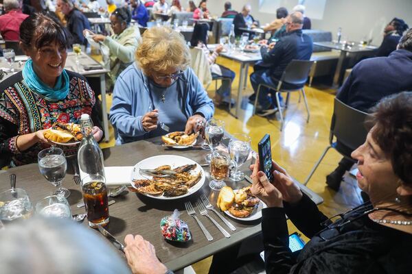 Enthusiastic guests take photos with the food in the dining room at the Compass Rose Cafe in Macon, Ga., on Friday, Dec. 12, 2025. (Abbey Cutrer/AJC)