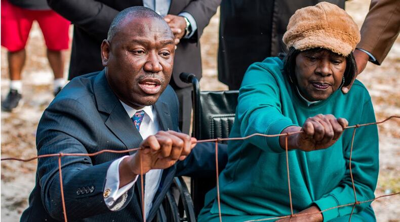 Tallahassee attorney Ben Crump and Camilla resident Gwen Lillian Thomas grip the cemetery fence during a Dec. 22 press conference. The fence was taken down on Thursday. (Contributed photo)