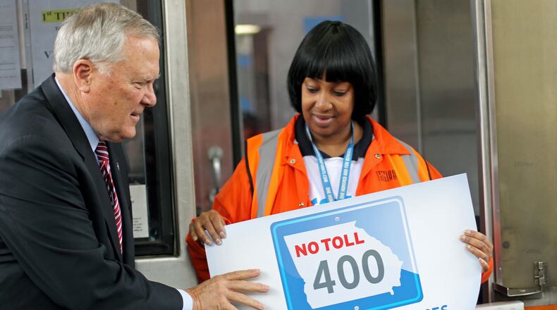 Gov. Nathan Deal and control room operator Yolanda Perry place a sign on the change basket to signify the closing of the GA 400 Toll Plaza Friday afternoon in Atlanta, Ga., November 22, 2013. The tool booth plaza opened on August 2, 1993. GA 400 was the state's first toll road. JASON GETZ / JGETZ@AJC.COM