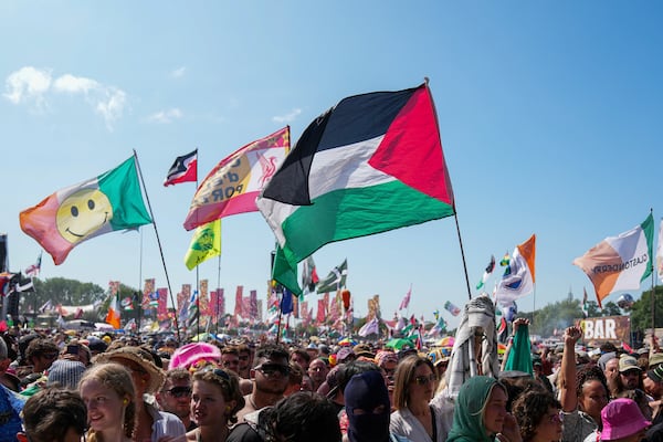 The flag of Palestine is waved in a crowd of festivalgoers at the hip hop trio Kneecap's performance during the Glastonbury Festival in Worthy Farm, Somerset, England, Saturday, June 28, 2025. (Scott A Garfitt/Invision/AP)