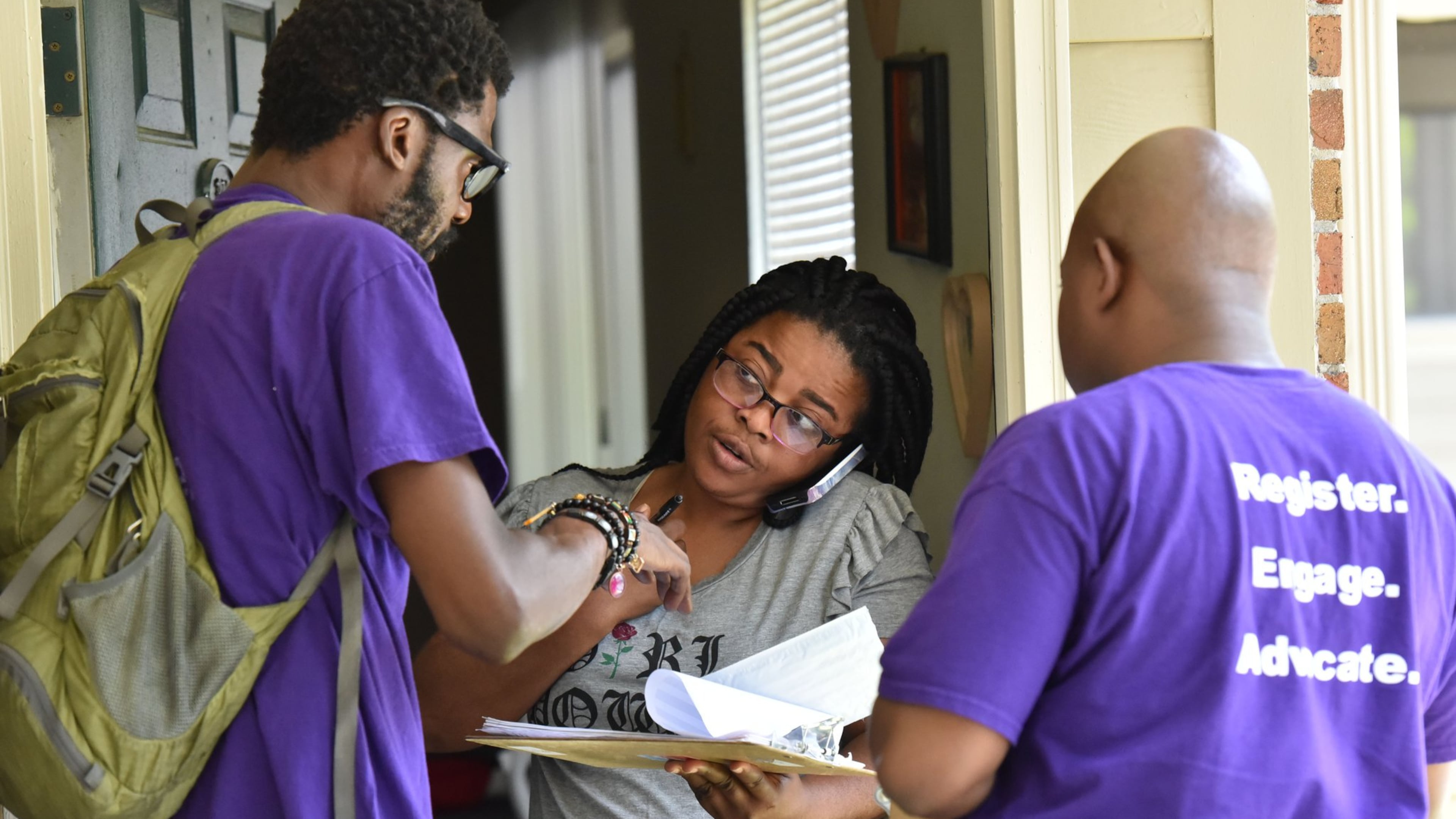 Corbin Spencer, right, field director of New Georgia Project and volunteer Rodney King, left, help Rueke Uyunwa register to vote. The influential group is shutting down after more than a decade. (Hyosub Shin/AJC 2017)