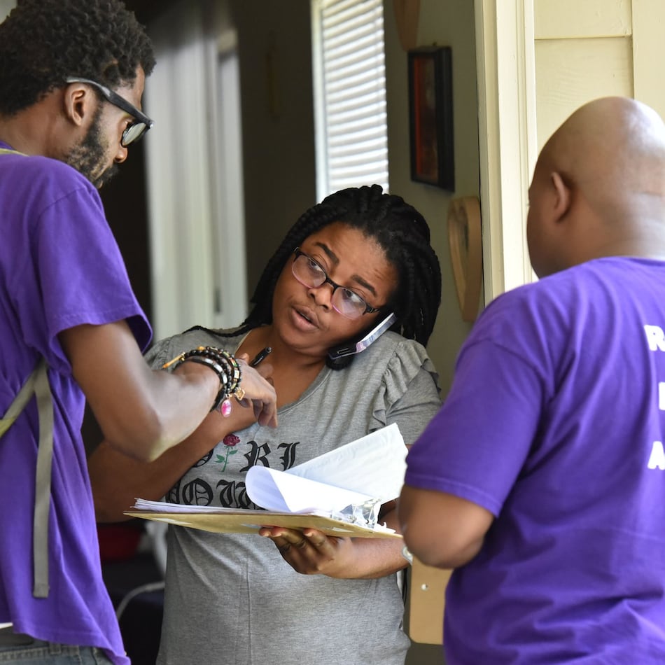 Corbin Spencer, right, field director of New Georgia Project and volunteer Rodney King, left, help Rueke Uyunwa register to vote. The influential group is shutting down after more than a decade. (Hyosub Shin/AJC 2017)