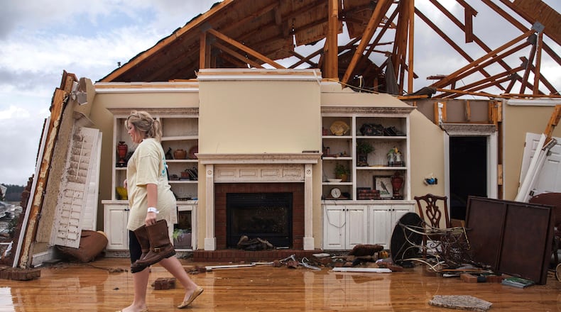 Jenny Bullard carries a pair of boots from her home that was damaged by a tornado, Sunday, Jan. 22, 2017, in Adel, Ga. Georgia Gov. Nathan Deal declared a state of emergency in several counties, including Cook, that have suffered deaths, injuries and severe damage from weekend storms. (AP Photo/Branden Camp)