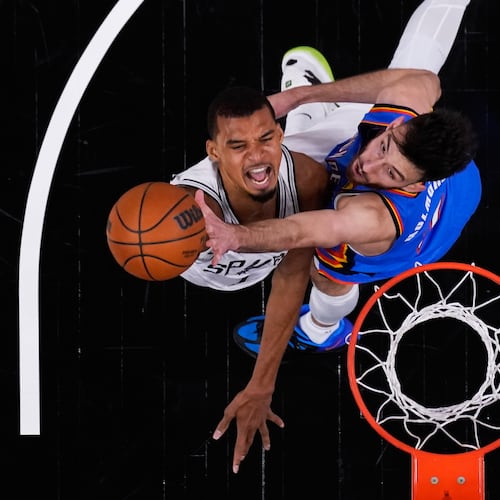 San Antonio Spurs forward Victor Wembanyama, left, scores against Oklahoma City Thunder center Chet Holmgren, right, during the first half in Game 4 in the Western Conference finals NBA basketball playoffs series in San Antonio, Sunday, May 24, 2026. (AP Photo/Eric Gay)