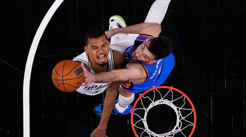 San Antonio Spurs forward Victor Wembanyama, left, scores against Oklahoma City Thunder center Chet Holmgren, right, during the first half in Game 4 in the Western Conference finals NBA basketball playoffs series in San Antonio, Sunday, May 24, 2026. (AP Photo/Eric Gay)
