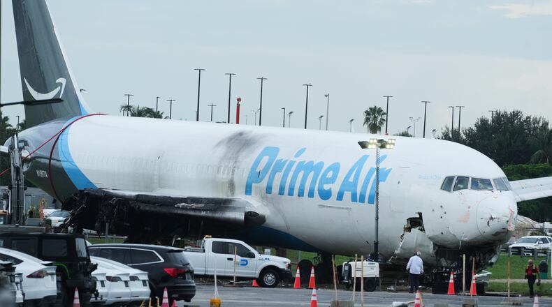 Workers inspect an Amazon cargo plane that overshot a runway four days ago at Miami International Airport, Thursday, Sept. 10, 2026, in Miami. (AP Photo/Marta Lavandier)