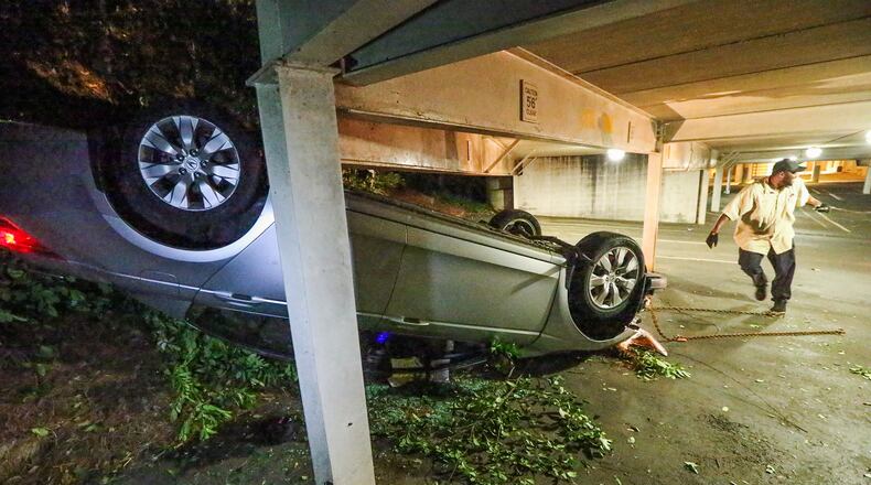 A tow truck operator works to remove a wrecked car from a Buckhead parking garage. JOHN SPINK / JSPINK@AJC.COM