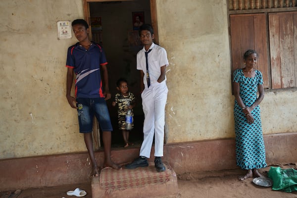 Kumarakulasingham Dinojan, 15, in school uniform, stands with his elder brother Vilvaraj Jethurshan, 16, left, at the doorway of their house in Mankindy, Sri Lanka, Tuesday, April 1, 2025. (AP Photo/Eranga Jayawardena)