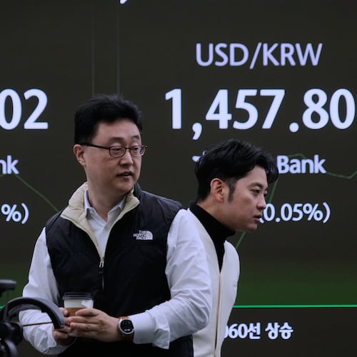 Currency traders pass by a screen showing the Korea Composite Stock Price Index (KOSPI), left, and the foreign exchange rate between U.S. dollar and South Korean won at the foreign exchange dealing room of the Hana Bank headquarters in Seoul, South Korea, Monday, Nov. 17, 2025. (AP Photo/Ahn Young-joon)