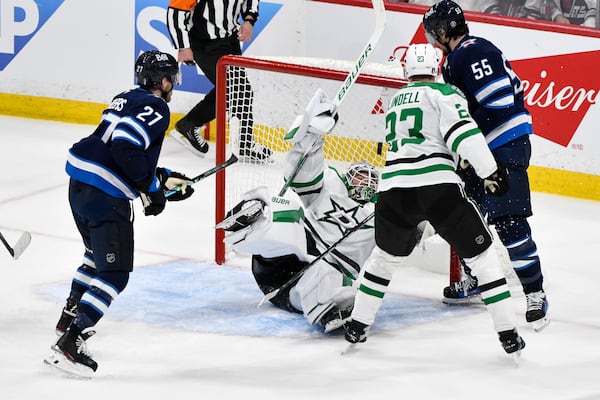 Dallas Stars goaltender Jake Oettinger (29) makes a save as Winnipeg Jets' Mark Scheifele (55) looks for the bouncing puck during second period NHL playoff hockey action in Winnipeg, Thursday, May 15, 2025. (Fred Greenslade/The Canadian Press via AP)