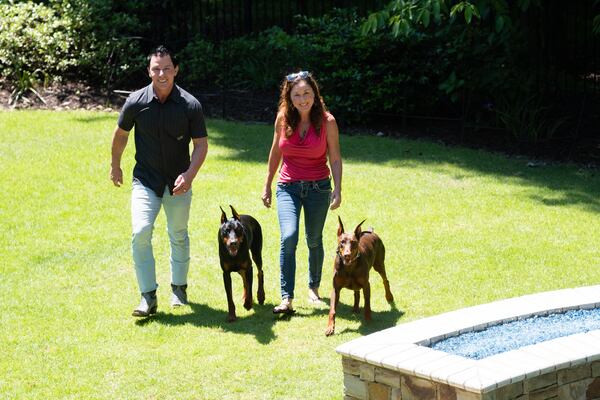 Matt and Laurel Nelson with their Doberman pinschers Legend and Lilac in the backyard of their home in the gated Ellard community in Roswell on Wednesday, May 13, 2026. (Ben Gray for the AJC)
