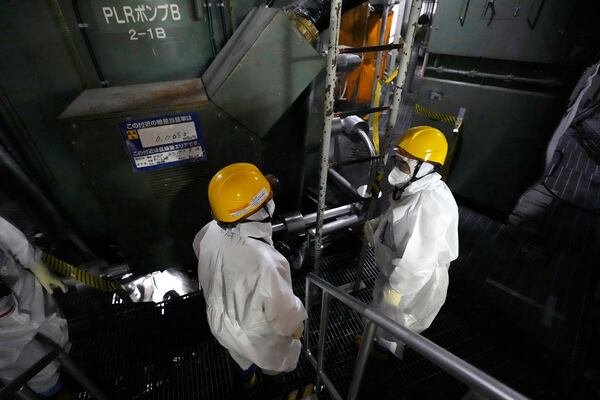 Tokyo Electric Power Company Holdings (TEPCO) employees speak as they take AP journalists to the area at the Unit 5 reactor pressure vessel, which survived the earthquake-triggered tsunami in 2011, at the Fukushima Daiichi nuclear power plant, run by TEPCO, in Futaba town, northeastern Japan, on Monday Feb. 20, 2025. (AP Photo/Eugene Hoshiko)