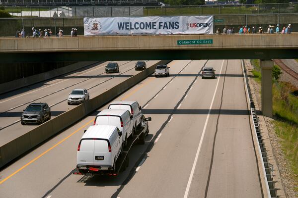 Vehicles travel along the Pennsylvania Turnpike passing under a pedestrian bridge splitting Oakmont Country Club during a practice round ahead of the U.S. Open golf tournament Wednesday, June 11, 2025, in Oakmont, Pa. (AP Photo/Charlie Riedel)