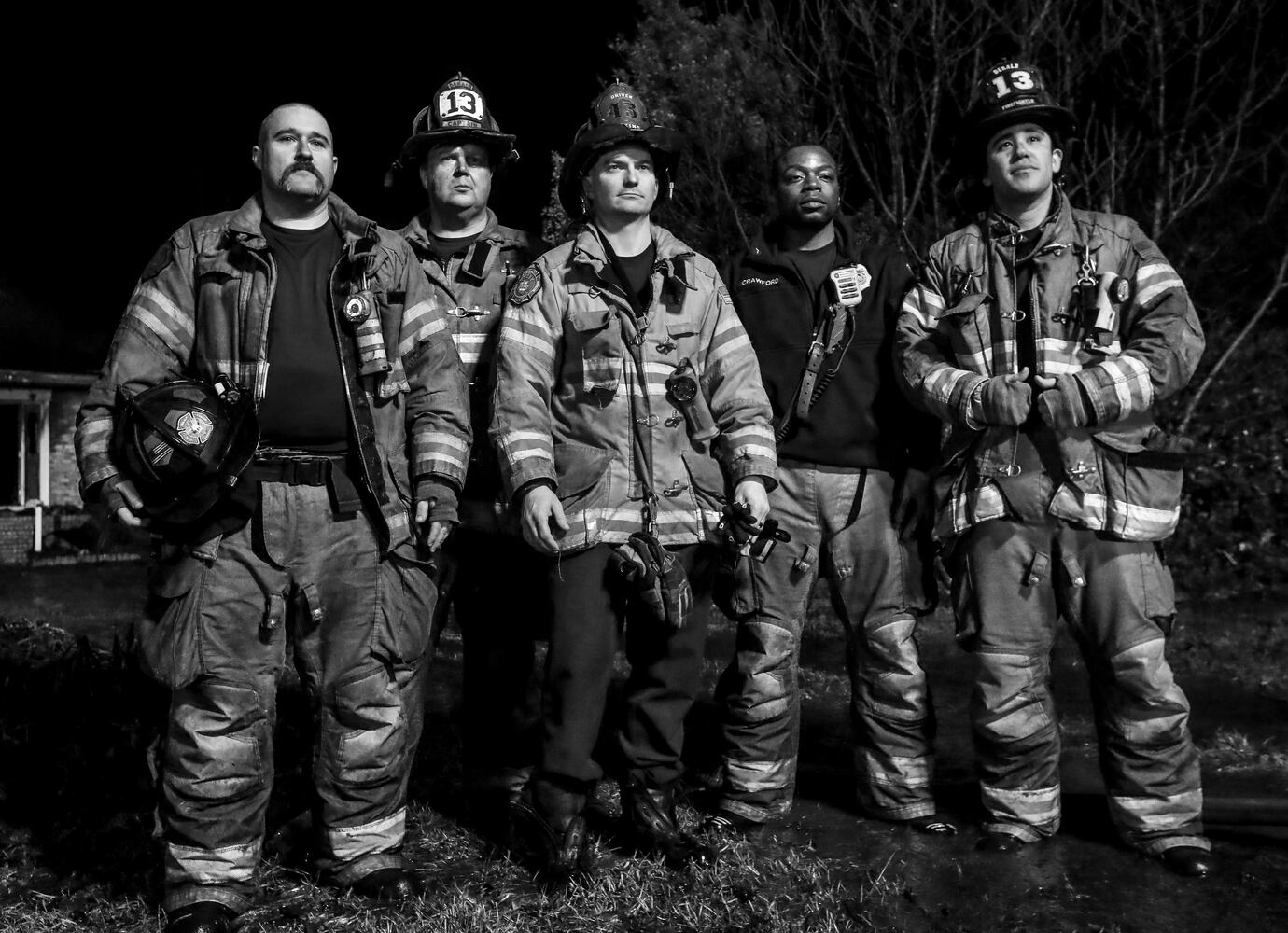 In this black-and-white image, DeKalb County firefighters are at the scene of Feb. 10, 2023, house fire on Whisper Wood Trail in a neighborhood south of Stone Mountain. No residents or firefighters were injured. (John Spink / John.Spink@ajc.com)

