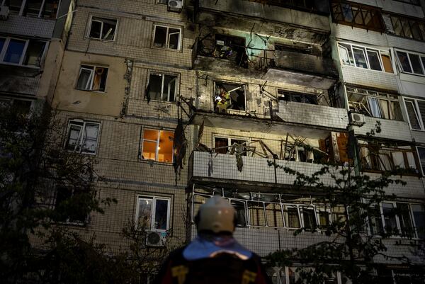 Emergency workers navigates his colleagues at the site of residential building damaged after a Russian attack in Kyiv, Ukraine, Saturday, May 24, 2025. (AP Photo/Alex Babenko)