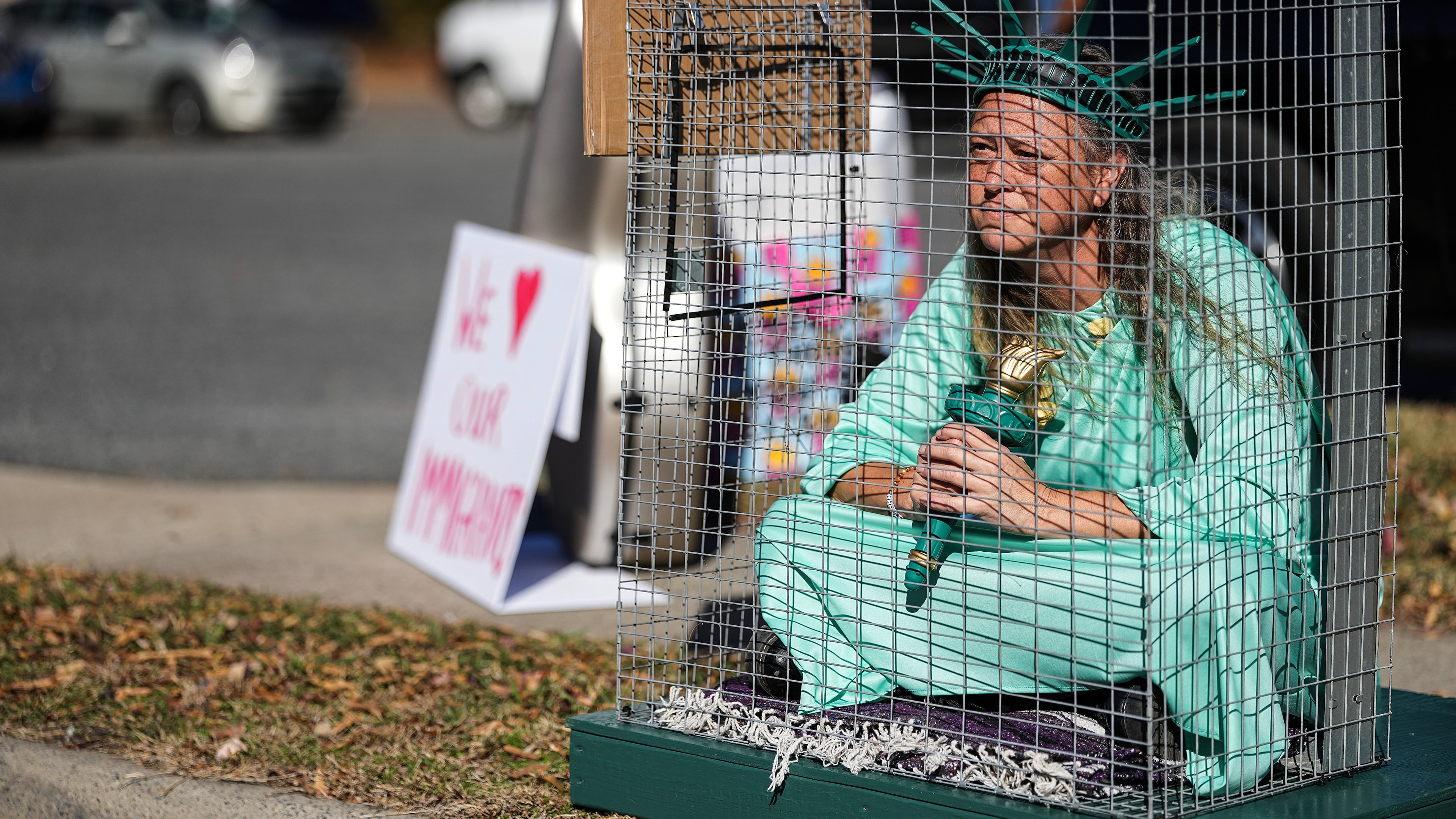 Shana Blake sits in a cage dressed as the Statue of Liberty to protest federal law enforcement presence in Charlotte, N.C. Monday, Nov. 17, 2025. (AP Photo/Matt Kelley)