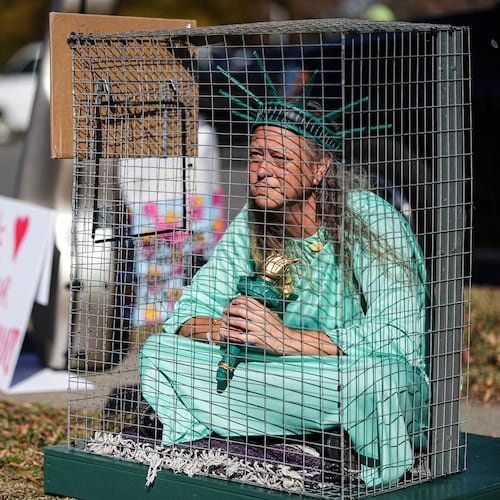 Shana Blake sits in a cage dressed as the Statue of Liberty to protest federal law enforcement presence in Charlotte, N.C. Monday, Nov. 17, 2025. (AP Photo/Matt Kelley)