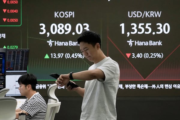 A currency trader works near a screen showing the Korea Composite Stock Price Index (KOSPI) and the foreign exchange rate between U.S. dollar and South Korean won, top right, at the foreign exchange dealing room of the KEB Hana Bank headquarters in Seoul, South Korea, Thursday, July 3, 2025. (AP Photo/Ahn Young-joon)