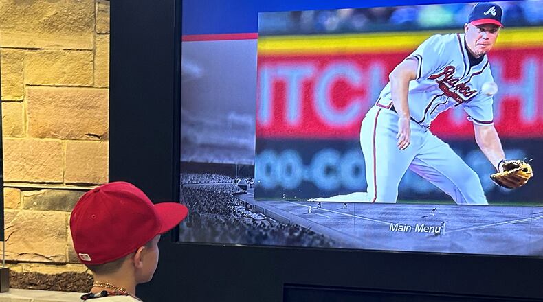 Baylor Skelton, age 8, whose favorite Braves player is Hall of Fame third baseman Chipper Jones, watches video of Jones on  a screen at Monument Garden at Truist Park on July 23, 2024. (Photo by Daniela Ramirez/The Atlanta Journal-Constitution)