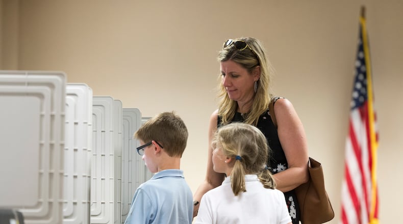 Dunwoody resident Kari Downing, center right, and her children Reagan, center right, and Thomas, center left, stand at a voting machine at DeKalb County Public Library in Dunwoody on April 18, 2017. Cobb, Fulton and North DeKalb residents cast ballots for the highly contested 6th Congressional District race. (DAVID BARNES / DAVID.BARNES@AJC.COM)