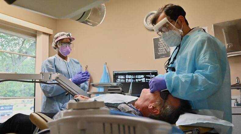 Dr. Daniel Galvez with hygienist Amanda Winn (left) treat a patient at Windy Hill Dentistry. (Hyosub Shin / Hyosub.Shin@ajc.com)