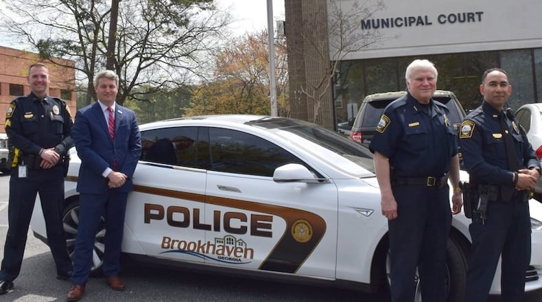 Sgt. Jake Kissel (left), Mayor John Ernst, Police Chief Gary Yandura and Officer Carlos Nino with Brookhaven's 2015 Tesla Model S, which will undergo performance tests at the Georgia Public Safety Training Center on Tuesday.