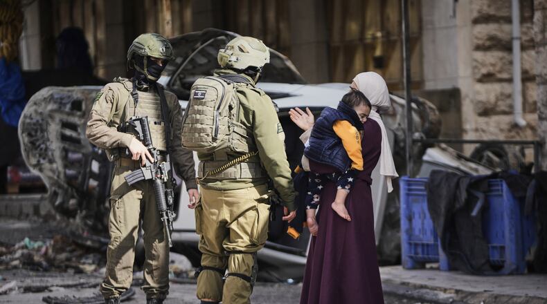 A Palestinian woman asks Israeli soldiers for access to her home during an army raid in the West Bank city of Hebron Monday, Jan. 19, 2026. (AP Photo/Mahmoud Illean)