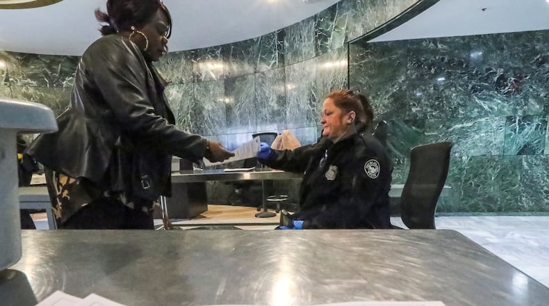 March 23, 2018: Kim Nelson (left) with the city of Atlanta IT department receives a flyer instructing employees not to logon to their computers from Atlanta police officer K. Wilkins (right) at the front doors of City Hall. (JOHN SPINK/JSPINK@AJC.COM)
