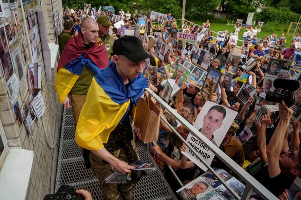 Ukrainian soldiers walk though human corridor with people holding photos of their missed relatives after returning from captivity after a POWs exchange between Russia and Ukraine, in Chernyhiv region, Ukraine, Monday, June 9, 2025. (AP Photo/Evgeniy Maloletka)