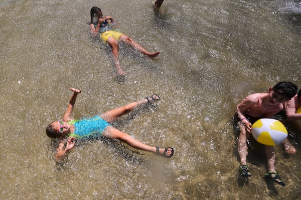 With temperatures hovering near 100 degrees, children cool off in the Frog Pond, on Boston Common, Tuesday, June 24, 2025, in Boston. (AP Photo/Charles Krupa)