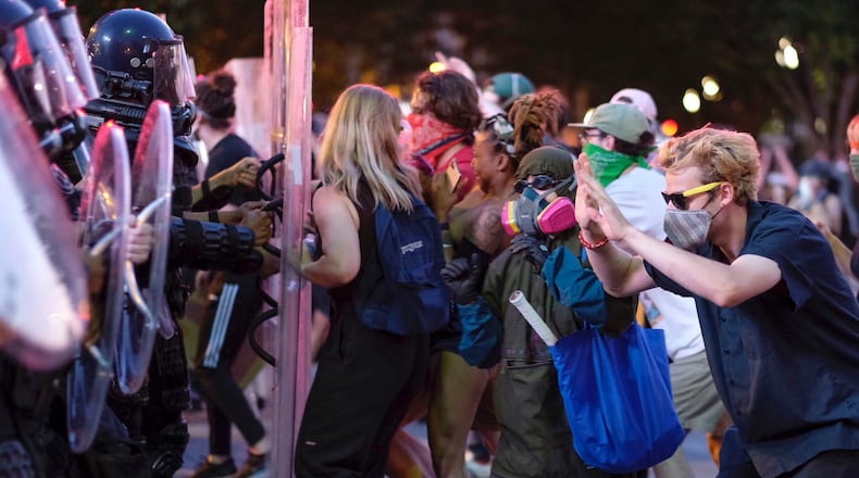 Protesters dodge tear gas and police Tuesday after the 9 p.m. curfew  in downtown Atlanta as protests continued for a fifth day.