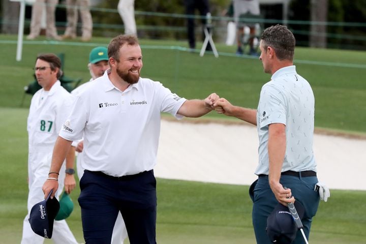 April 8, 2021, Augusta: Shane Lowry, left, gives Justin Rose a fist bump as they finish their first round on the eighteenth hole during the Masters at Augusta National Golf Club on Thursday, April 8, 2021, in Augusta. Curtis Compton/ccompton@ajc.com