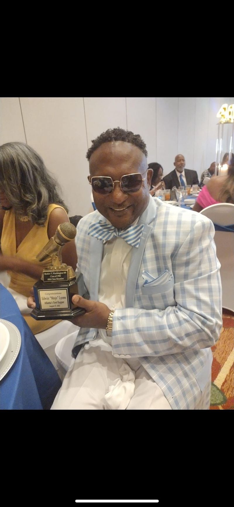 Edwin 'Mojo' Lyons smiles with the trophy presented to him by reunion president Valerie Williams during the Booker T. Washington Class of 1982 40th reunion in 2022. His high school class kickstarted the recognition of Lyons as Atlanta's first rapper, a period of recognition that has continued into the celebration of 50 years of hip-hop in 2023.