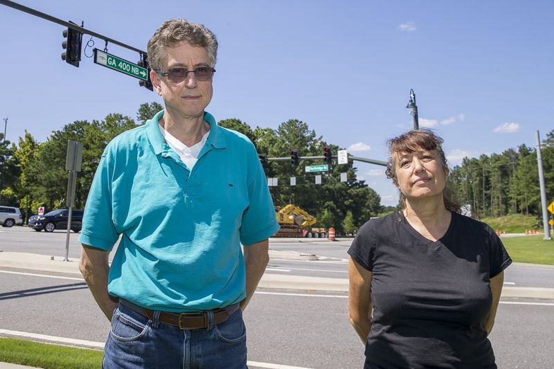Sandy Springs residents Kayla Engle-Lewis (right) and Jeff Strode (left) stand for a portrait near the offramp to Northridge Road on northbound GA 400 in Sandy Springs, Wednesday, July 24, 2019. Cities along Ga. 400 are talking about petitioning the Georgia Department of Transportation to have a say in how the new highway is being designed as part of the ongoing project. (Alyssa Pointer/alyssa.pointer@ajc.com)