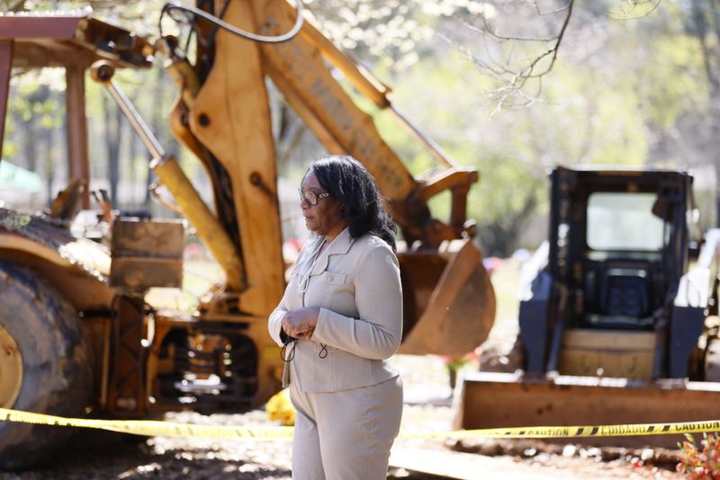 Trina Baynes stands in front of the site where her mother should have been buried more than two weeks ago. A broken backhoe sitting at her mother's gravesite at Carver Memorial Gardens had prevented her mother's proper burial.