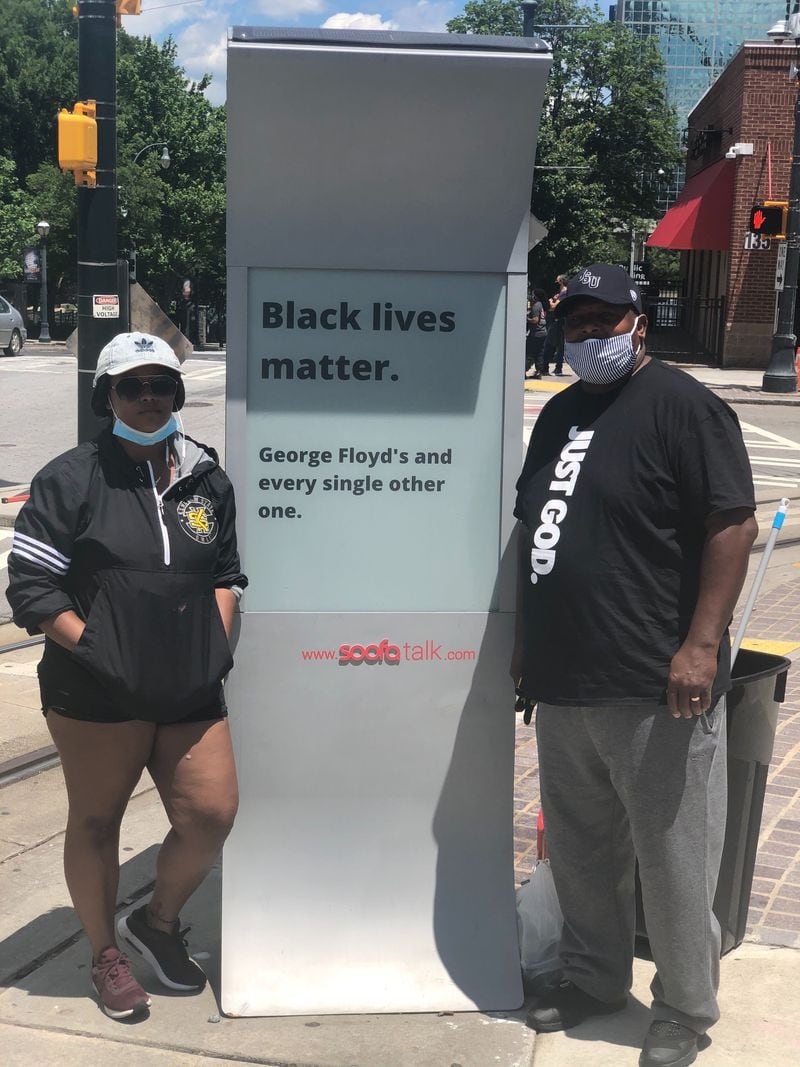 Sakeema Freeman and her father Veree got to work Saturday morning cleaning graffitti off of a sign in downtown Atlanta after a night of violence. GREG BLUESTEIN/STAFF