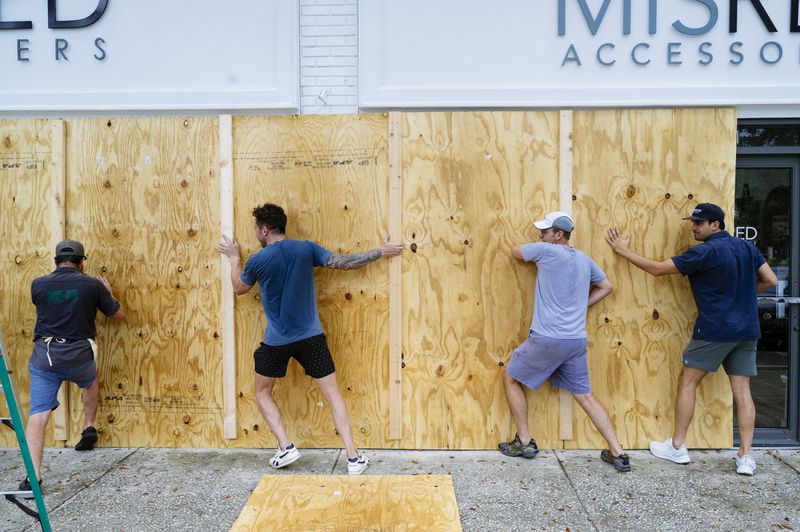 Workers board up a shopfront on Central Ave in St. Petersburg, Fla. in anticipation of Hurricane Ian on Sept. 27, 2022. Preparations have begun in Florida, where a combination of dangerous storm surges, flooding and powerful winds are expected in the coming days. (Bob Croslin/The New York Times)