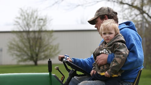 A 4-year-old sits on a riding mower with his father in Kellerton, Iowa.